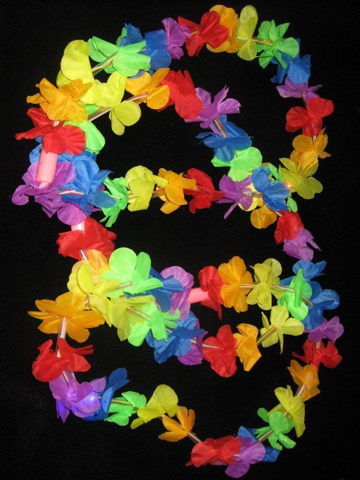 Colorful Hawaiian flower leis in vibrant red, yellow, green, blue, pink, and orange hues.